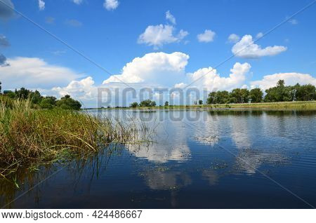 The Bank Of The Berezovka River Is A Tributary Of The Volga. In Summer, Green Trees And Clouds Are R