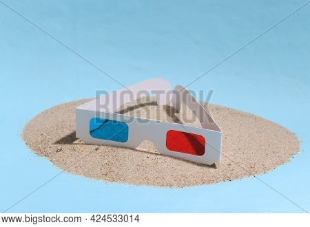 3d Glasses On A Sandy Island. Blue Studio Background.