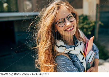 Candid Portrait Of A Happy Young Student Woman With Long Red Hair Smiling And Wearing Transparent Ey