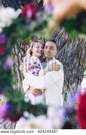 Young People Are Posing In Traditional Folk Costumes. Cossacks Man And Woman In Wreaths And Embroide