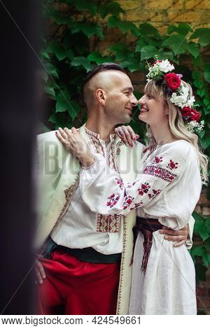 Young People Are Posing In Traditional Folk Costumes. Cossacks Man And Woman In Wreaths And Embroide