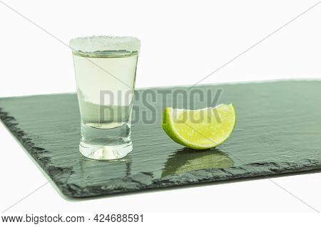 Shot Glass With Tequila And Lime On A White Background. A Slice Of Lemon Close-up On A Stone Cutting