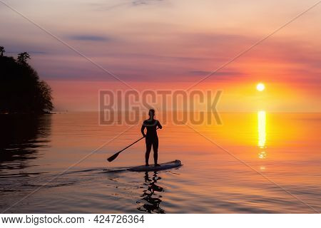 Adventurous Woman On A Paddle Board Is Paddeling In The Pacific West Coast Ocean. Sunset Sky Art Ren