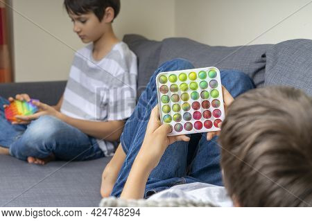 Teenage Boys Playing With Rainbow Pop-it Fidget Toys At Home. Push Pop-it Fidgeting Game Helps Relie