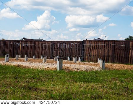 The Process Of Building A Private House. Columnar Foundation On The Background Of A Wooden Fence.