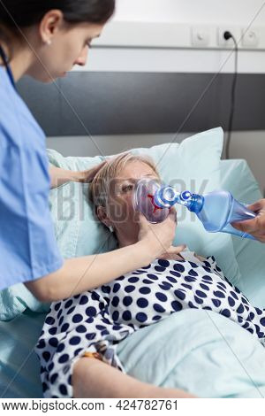 Doctor And Nurse Helping Sick Hospitalized Senior Woman Breath, With Ambu Bag During Resustacitor Pr