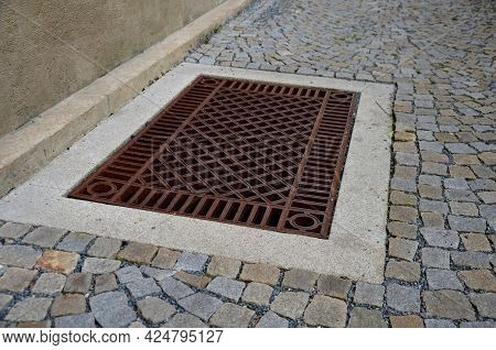 Shady Corner Behind The House By A Road Of Granite Cubes. Metal Ventilation Grilles In The Tiles Res