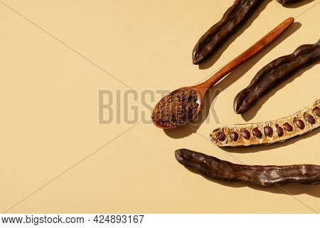 Carob Bean And Powder Flat Lay On Yellow Or Brown Background, Top View, Copy Space