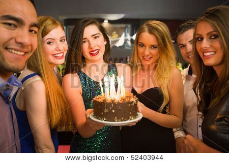 เพื่อนมีความสุขฉลอง brithday หนึ่งถือเค้กวันเกิดกล้องในไนท์คลับ