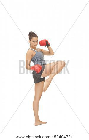 Concentrating sporty brunette kick boxing on white background