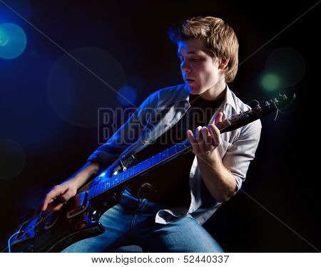 portrait of young man with guitar on dark background