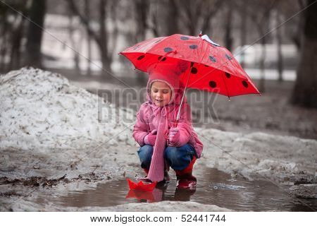 little girl playing in a pool with a paper boat