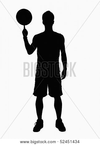 Silhouette of basketball player spinning basketball on finger.