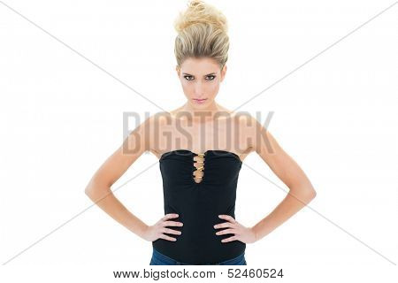 Serious sexy blonde model standing with hands on hips on white background