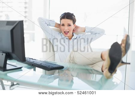 Pleased stylish brunette businesswoman relaxing with feet up in bright office