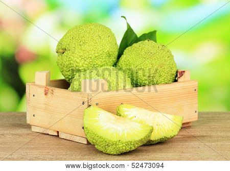 Osage Orange fruits (Maclura pomifera) in crate, on wooden table, on nature background
