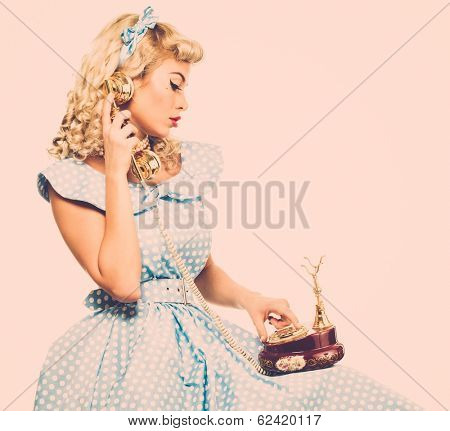 Coquette blond pin up style young woman in blue dress with vintage phone 