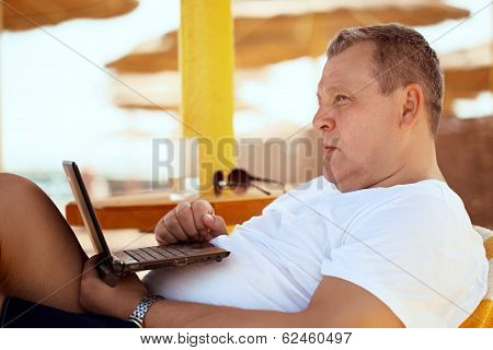 Man relaxing with a laptop at beach resort