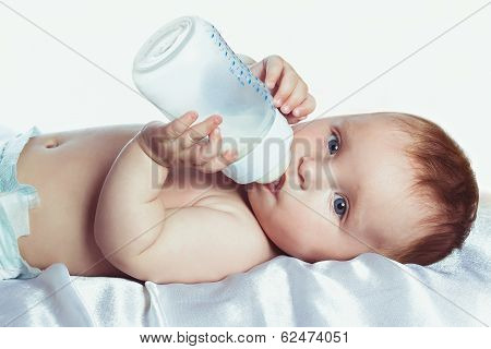 Baby with blue eyes drinking from a bottle