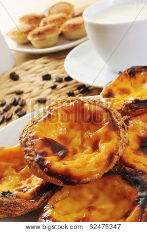 closeup of some pasteis de nata and some pasteis de feijao, typical Portuguese pastries, on a set table