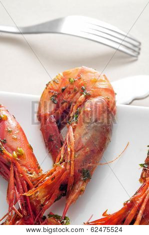 closeup of a plate with spanish shrimps cooked with garlic and parsley on a set table