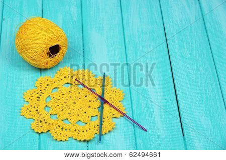 Yellow yarn for knitting with napkin and spokes on wooden table close-up