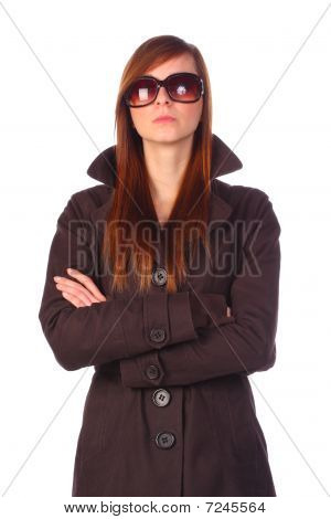 Elegante jovem determinada em Trenchcoat com óculos de sol com os braços cruzados