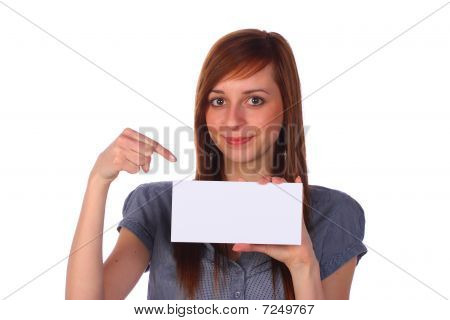 Menina bonita sorridente segurando um cartão de nota em branco e apontando nele, isolado no branco
