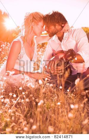Handsome man serenading his girlfriend with guitar on a sunny day