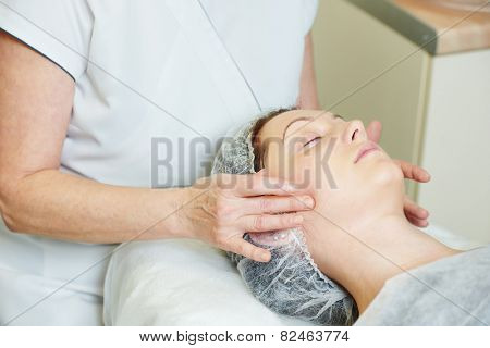beautician worker with paintbrush applying facial cosmetic mask to female client in beauty salon