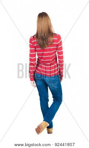 back view of standing young beautiful  blonde woman in jeans. girl  watching. Rear view people collection.  Isolated over white background. Throwing his legs blonde in striped red sweater looks ahead