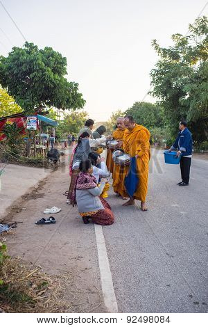 locals give food offerings to Buddhist monks