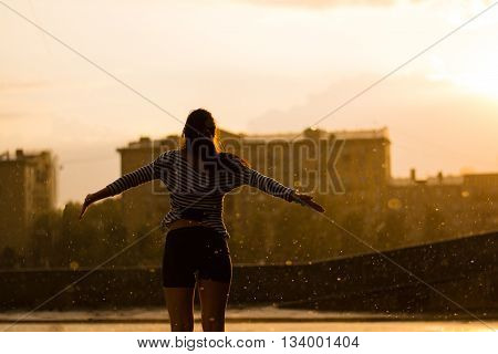 Woman stand under the rain on sunset background