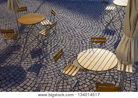 Outdoor German cafe seating with round tables and wooden chairs