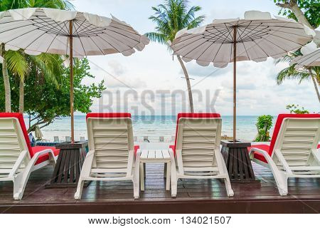 Beautiful beach chairs with umbrella around outdoor swimming pool neary sand and sea