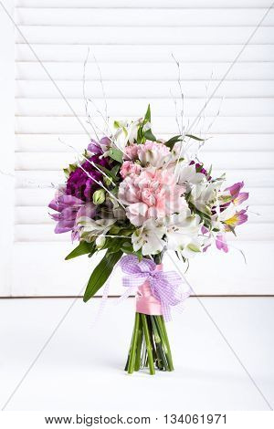 Pastel bouquet from pink and purple gillyflowers and alstroemeria on white shutter background