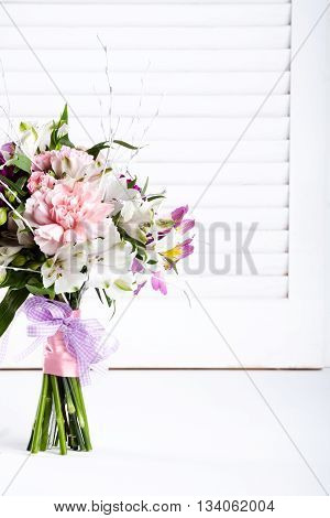 Pastel bouquet from pink and purple gillyflowers and white alstroemeria on white shutter background