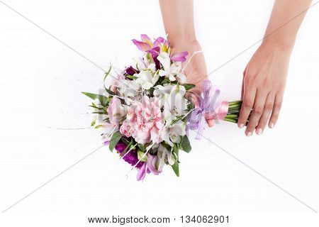 Hands holding a pink bouquet from gillyflowers and alstroemeria on white