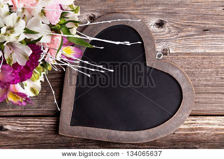 Mother's Day bouquet from gillyflowers and white alstroemeria on old rustic wooden background with wooden heart