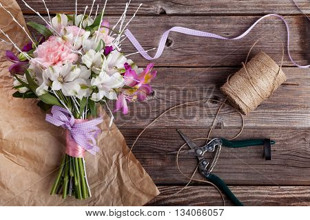 Rustic bouquet from gillyflowers and white alstroemeria on old rustic wooden background with wooden heart and scissors with paper