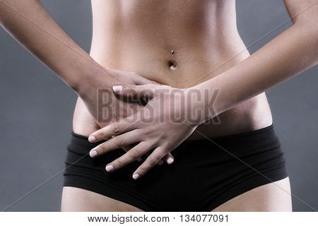Body pain. Close up studio shot of woman. Woman suffering from underbelly pain