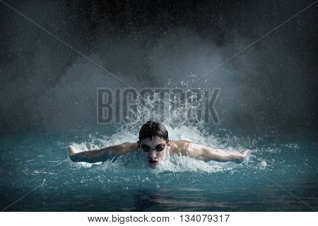 Swimer in waterpool. Butterfly style of swimming.