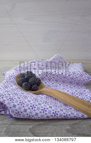 Blackberries in a spoon on wooden background