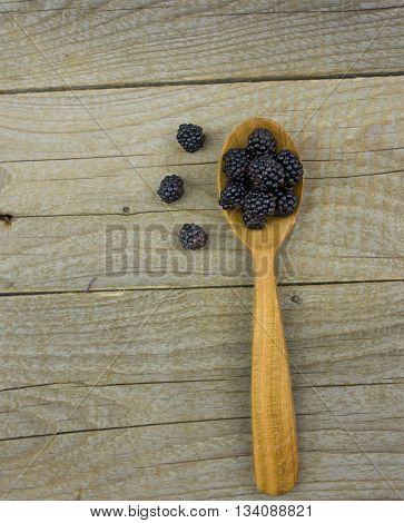 Blackberries with spoon on wooden background closeup shot