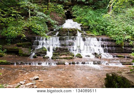Waterf flows directly from rock on a limestone cliff.