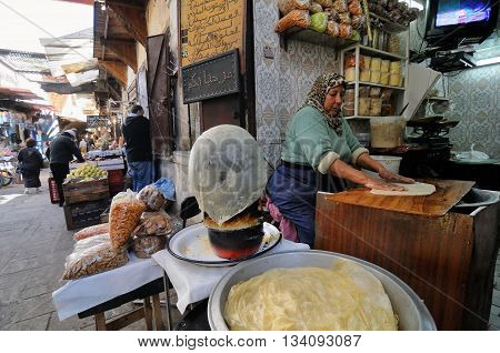 FES - MARCH 10: Unknown woman trades a traditional bread in a Market (souk) in a city Fes in Morocco. The market is one of the most important attractions of the city. March 10, 2012 Fes, Morocco.