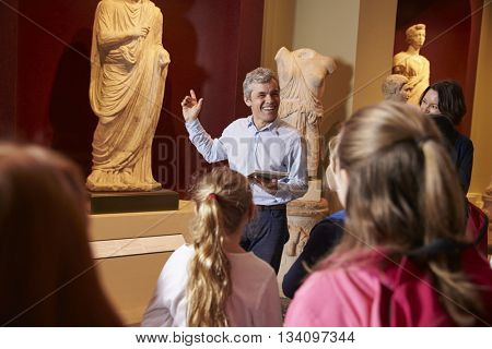 Pupils And Teacher On School Field Trip To Museum With Guide