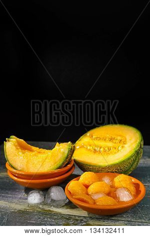 Fresh cantaloupe melon and ice on dark background copy space hot summer concept