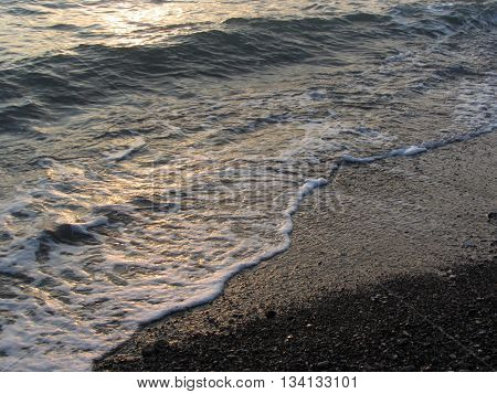 White foam glows between stony coast and water surface. Marina di Cecina Livorno Italy
