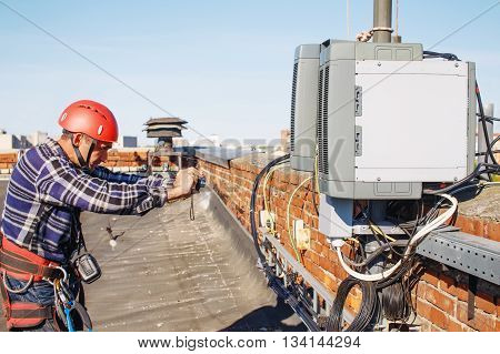 worker finished work and takes photos for the report. quality control. tower technician installed telecommunication equipment on the roof of the building. a good worker photographed the completed part of the work to check